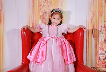 Little asian girl dressed as a princess. Child in pink princess dress over vintage background.
