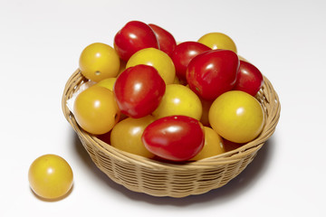 Raw multicolored cherry tomatoes in the dish closeup, ready to eat, isolated on white, vegan food.