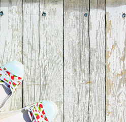 White with red berries sneakers on a white wooden background. Summer shoes top view. Colored...