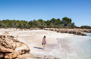 Mujer joven paseando en una idílica playa de arena blanca de la costa mediterránea. 