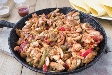 Chicken stew with red and green pepper, with red onion, pickled cucumber and spices in a frying pan.