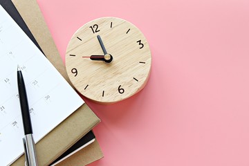 Still life, business, office supplies or education concept : Top view or flat lay of notebooks, calendar, clock and pen on pink background, ready for adding or mock up