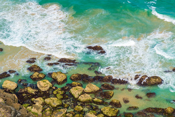 Aerial view over green turquoise water waves in Byron Bay, Australia. Nature background with ocean waters and rocks in sunny day.