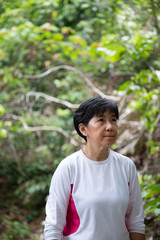 Asian senior woman hiking through the rain forest