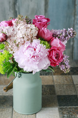 Floral arrangement with pink roses, peonies and lilacs.