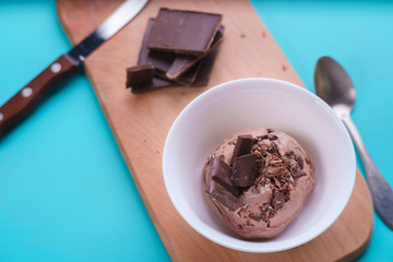 Chocolate ice cream with chocolate crumbs in white bowl and broken chocolate bar on background. Delicious summer treat, cafe concept