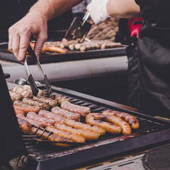 Man cooking delicious juicy meat sausages on the grill outdoor