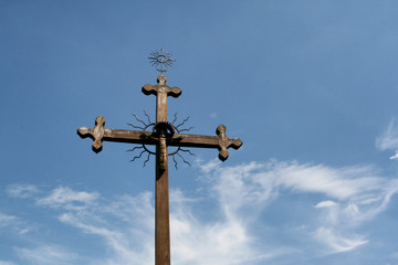 stary zdobiony krzyż rzymskokatolicki na tle blękitnego nieba