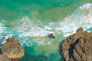 Aerial view over green turquoise water waves in Byron Bay, Australia. Nature background with ocean waters and rocks in sunny day.