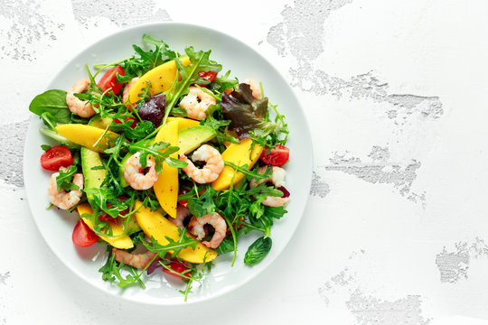 Fresh Avocado, Shrimps, Mango salad with lettuce green mix, cherry tomatoes, herbs and olive oil, lemon dressing. healthy food