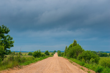 Fototapeta na wymiar an empty rural clay road in rainy weather, in the sky