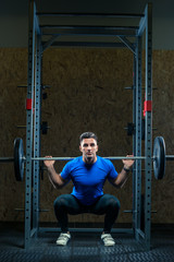 Fototapeta na wymiar strong young bodybuilder with a barbell in the gym is practicing