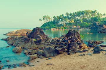 old boat in the rocks at the beach of Goa. Tinted.