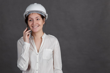 Young brunette woman in a protective helmet talking on the phone