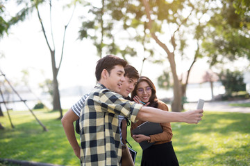 Friends in the park looking using smartphones video call selfie