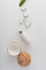 Fototapeta na wymiar Homemade coconut products with half and whole coconut on white wooden table background. Oil, scrub, milk and lotion from top view. Good for space and background.