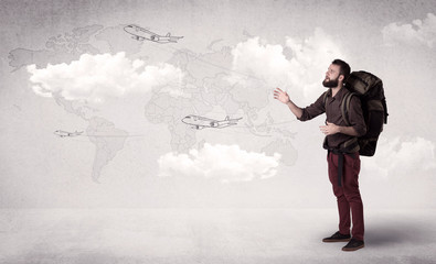 Handsome young man standing with a backpack on his back and planes in front of a world map as a background 