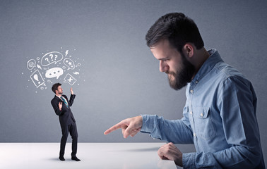Young professional businessman being angry with an other miniature businessman who has drawn speech...
