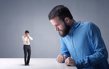 Young professional businessman being angry with an other miniature businessman 
