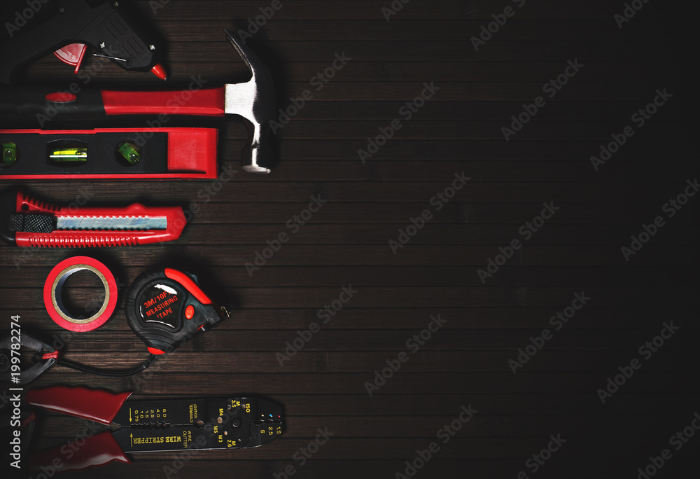 Wall mural tools for home repair in red style on a black wooden background