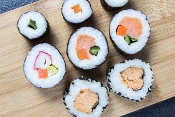 Various kinds of sushi on the wooden background.