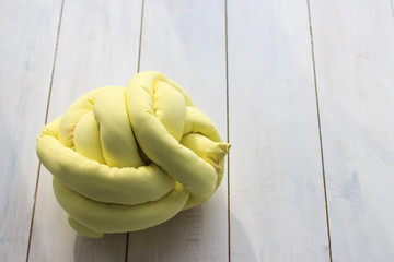Cute peach colored knot pillow on the indoors background. The original cushion knot, fist. Textiles