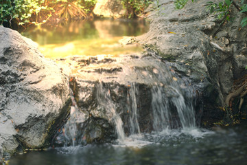 Small waterfall on pond with sun flare