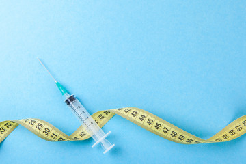 Syringe with a needle and yellow measuring tape. Injections for body beauty and weight loss. Drug...