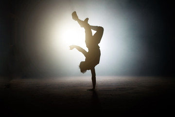man showing a one-handed handstand with legs on the bright stage. kind of freeze