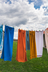 View of colorful bath towels drying on a rope in the garden on a bright sunny day