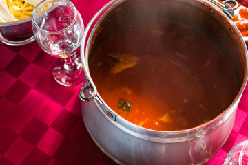 Close up and top view of a spicy fish stew on a red table cloth, a popular dish in eastern Croatia