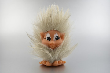 Troll toy stock images. Elf on a silver background. Vintage hairy toy. Gray furry troll