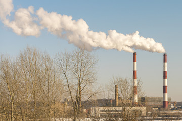 Two large smoking pipes against the blue sky. White thick smoke.