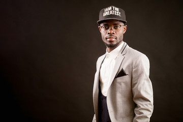 close up photo of rapper in cap wearing formal clothing