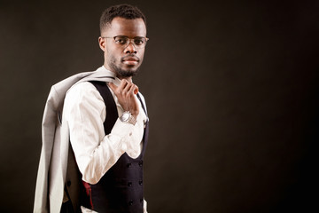 side view image of young Afro businessman in white shirt and black vest holding a jacket isilated...