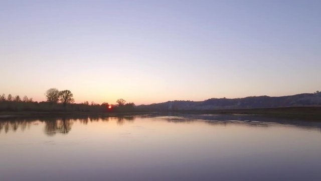 Overgrown broad river sunset sky reflection on water - aerial view