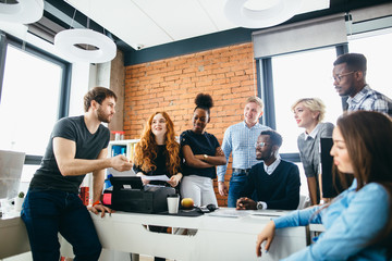 young handsome Caucasian guy with beard and moustache is motivating workers to start up risky...