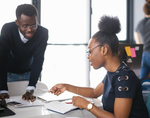 black nice students in glasses are studing in the college. male tutor is helping to female who has...