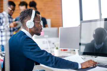side view close up portrait of serious Afro student with headphones preparing for seminar in the university. write a graduation paper, course work