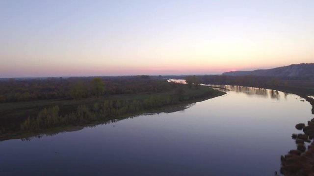 Overgrown broad river sunset sky reflection on water - aerial view
