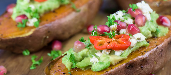 Baked sweet potatoes with guacamole, feta cheese and pomegranate - bataty - closeup - banner