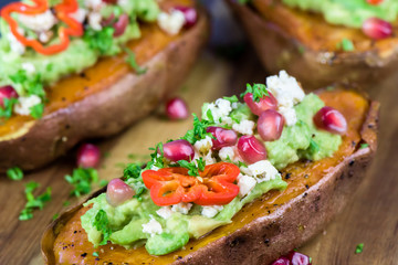 Baked sweet potatoes with guacamole, feta cheese and pomegranate - bataty - closeup