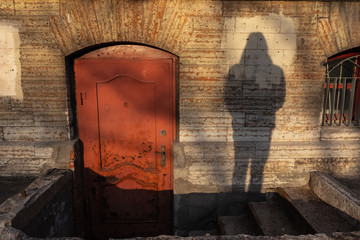 Shadow of human try to open the old red door