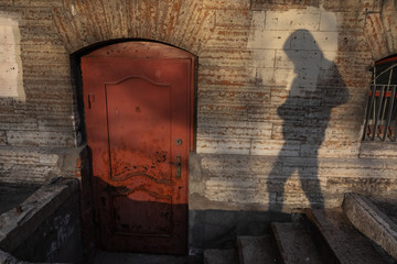 Shadow of human try to open the old red door