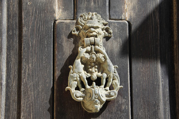 ozdobna bogato rzeźbiona kołatka na drewnianych drzwiach