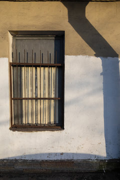 a window on the wall and a shadow from the pipe
