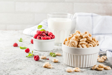Healthy breakfast ingredients. Breakfast cereal corn rings, milk or yogurt glass, raspberries and...