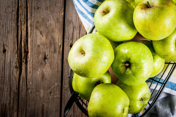 Fresh raw organic farm green apples in black metal basket, old rustic wooden background, copy space top view