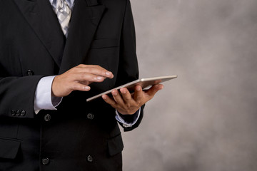 Business man with black suit using telephone or tablet for chech his work.