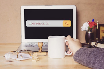 muslim woman drinking a coffee and searching cost per click in search bar
